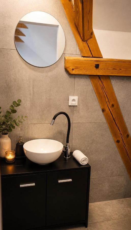 Apartmán Javor — umyvadlo s kulatým zrcadlem a dřevěným trámem