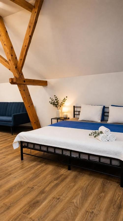 Apartmán Lípa — manželská postel pod dřevěnými trámy podkroví